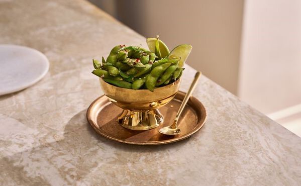 Edamame beans sprinkled with chilli and salt in a gold bowl, simple protein snack idea.
