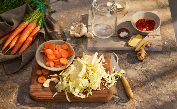 Chopped cabbage and carrots on a board with garlic, ginger and spices ready to make the homemade kimchi recipe.