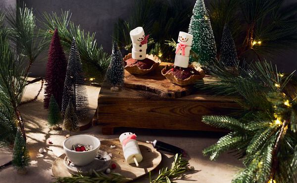 Christmas snowmen red velvet cakes decorated with marshmallows in a festive forest scene.