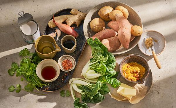 Fresh ingredients for Asian-inspired vegetarian stamppot recipe, including sweet potatoes, bok choi, coconut milk and spices.