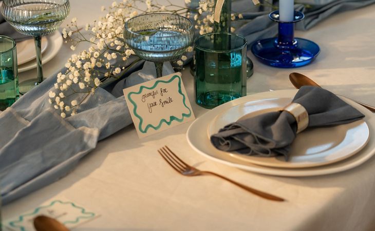 A warm, elegant tablescape featuring festive food, candles, and sparkling drinks on a marble table set for a cosy gathering.