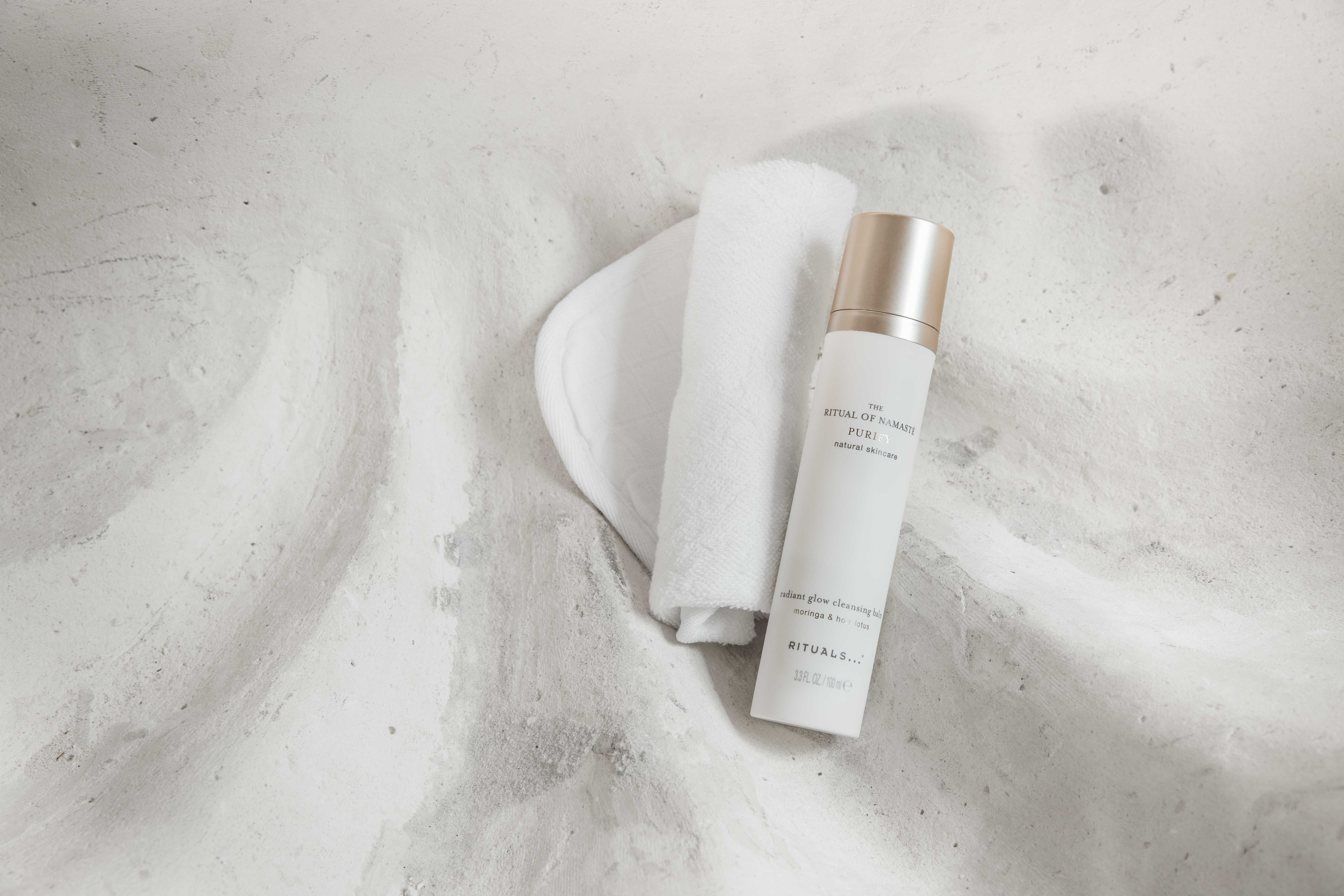 The Ritual of Namaste cleansing foam and cloth on a marble surface for double cleansing skincare.