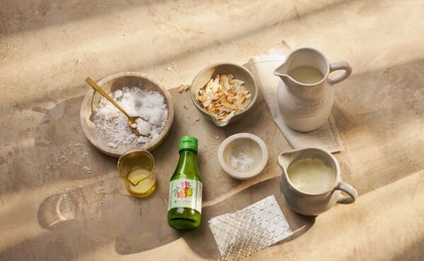 Ingredients for yuzu panna cotta recipe, including yuzu juice, cream, almonds and sugar, arranged on a stone surface.